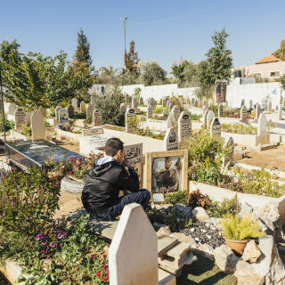 WEST BANK, Jenin Camp - A boy sits next to the grave of martyr Mateen Dabaya, 20, who was killed during an Israeli army raid into Jenin Camp on October 14, 2022, at the Martyrs' Cemetery at Jenin Refugee Camp in the Occupied West Bank on Thursday, January 19, 2023. 2022 has been the deadliest year for West Bank Palestinians in nearly two decades. 167 Palestinians have been killed in the West Bank and Occupied East Jerusalem, almost as many as in 2005 at the end of the Second Intifada. An additional 53 Palestinians have been killed in Gaza during 2022. Most of the Palestinians were killed by soldiers serving in the Israel Defense Forces (IDF), some others by settlers and security guards. In March 2022, the IDF started a military operation dubbed 