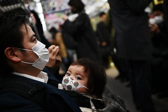 Un père et son enfant, dans le métro à Tokyo, le 9 mars 2020.(Photo by CHARLY TRIBALLEAU / AFP)