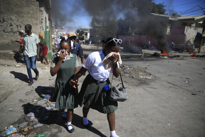 De écolières passent à proximité d’une barricade en feu, lors d’une manifestation de policiers à Port-au-Prince, le 26 janvier 2023.