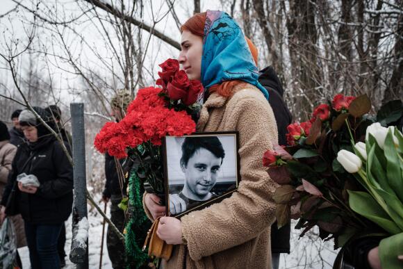 Kateryna Avdeyeva tient le portrait de son ami orphelin, dans un cimetière de Sloviansk, le 30 janvier 2023.