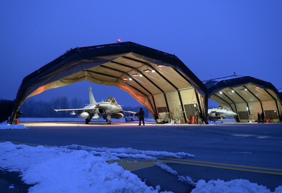 Deux shelters abritent deux Rafale C avec de la neige au premier plan. Le 1er décembre 2022, une alerte de permanence opérationnelle s'est déclenchée dès la première journée de prise d'alerte du détachement français dans le cadre d'enhanced Air Policing en Lituanie.