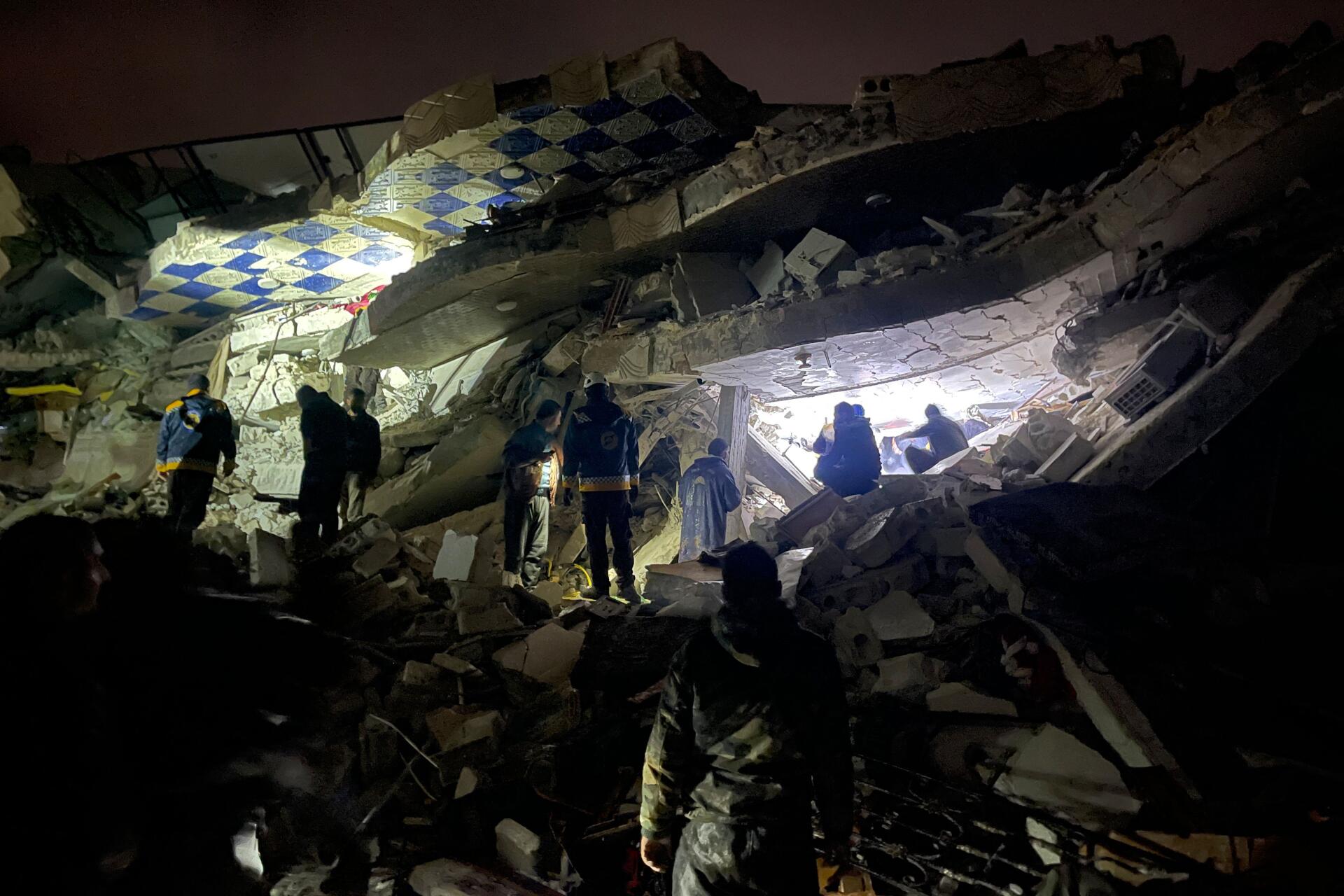 Peu après le tremblement de terre, des secouristes syriens (casques blancs) et des civils recherchent des victimes et des survivants parmi les décombres d’un bâtiment, dans la campagne du nord de la province syrienne d’Idlib, à la frontière avec la Turquie, tenue par les rebelles, tôt le 6 février 2023. Le séisme est survenu en pleine nuit (à 4 h 17 soit 2 h 17 heure de Paris).