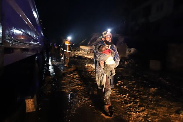 Un membre des casques blancs porte un enfant sauvé des décombres dans la ville de Zardana, dans la campagne de la province d’Idlib, au nord-ouest de la Syrie, tôt le 6 février 2023.