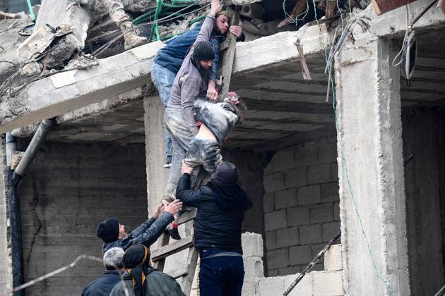 Los residentes recogen a una niña herida de los escombros de un edificio derrumbado luego de un terremoto en la ciudad de Jandairis en el campo de la ciudad de Afrin en el noroeste de Siria, parte de la provincia de Alepo controlada por los rebeldes el 6 de febrero de 2023.