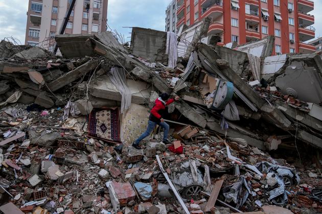 Un hombre busca personas en un edificio destruido en Adana, Turquía, el lunes 6 de febrero de 2023.