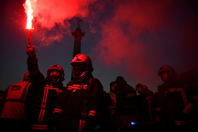 French firefighters burn a flare on the Place de la Bastille during a demonstration on the third day of nationwide rallies and strikes against a pensions reform plan in Paris on February 7, 2023. 