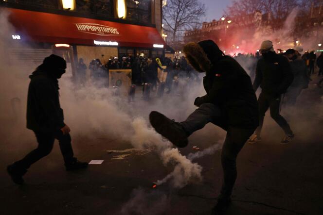 A protester kicks back a tear gas canister as clashes erupt during a demonstration on the third day of nationwide rallies and strikes against a pensions reform in Paris on February 7, 2023. 