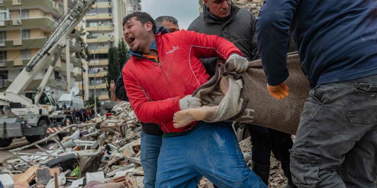 TOPSHOT - A rescuer reacts as he carries a body found in the rubble in Adana on February 6, 2023, after a 7.8-magnitude earthquake struck the country's south-east. The combined death toll has risen to over 1,900 for Turkey and Syria after the region's strongest quake in nearly a century on February 6, 2023. Turkey's emergency services said at least 1,121 people died in the 7.8-magnitude earthquake, with another 783 confirmed fatalities in Syria, putting that toll at 1,904. (Photo by Can EROK  / AFP)