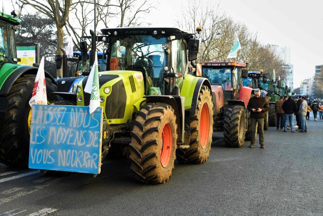 Los agricultores se paran junto a los tractores y un cartel 