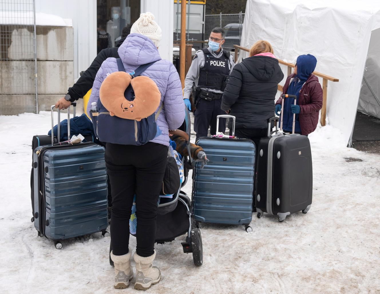 Una familia de migrantes colombianos con un oficial de la Real Policía Montada de Canadá, el 9 de febrero de 2023, después de cruzar la frontera hacia los Estados Unidos en Roxham Road.