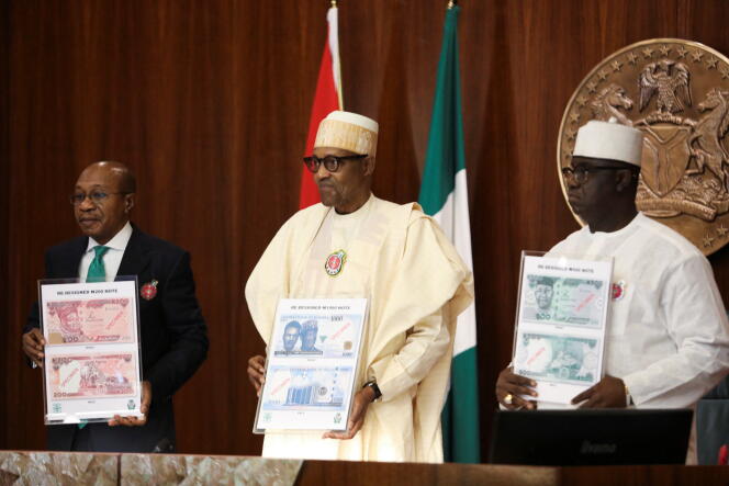 Le président nigérian Muhammadu Buhari (au centre) et le gouverneur de la Banque centrale Godwin Emefiele (à gauche) présentent les nouveaux nairas à Abuja, le 23 novembre 2022.