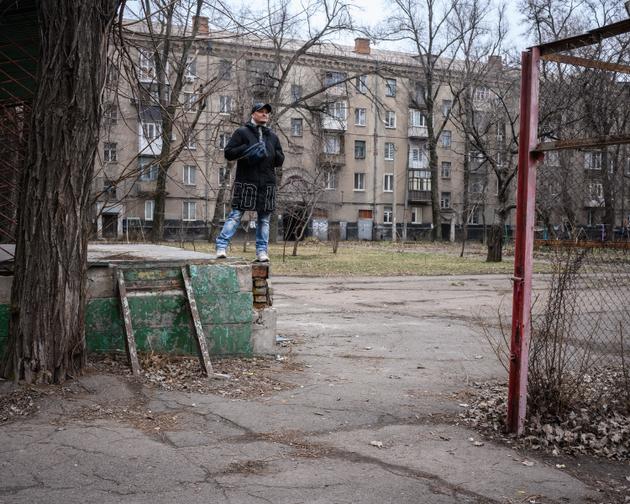 Denys Manzhosov, 24 de enero de 2023, en un jardín en Kryvy Rih, donde él y Volodymyr Zelensky jugaban cuando eran niños.  Al fondo, el edificio donde vivieron los padres de Volodymyr Zelensky cuando llegaron a esta ciudad. 