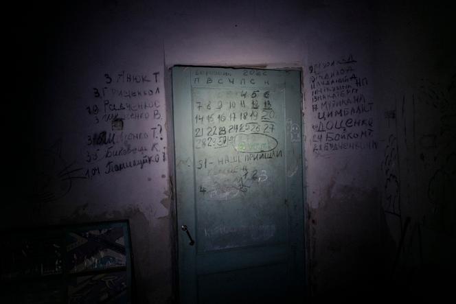 La lista de personas que murieron durante la ocupación del pueblo por los rusos está inscrita con carbón en la pared del sótano de la escuela donde los habitantes estaban encerrados.  A la derecha, los que murieron en el sótano, a la izquierda, los asesinados por los rusos.  En Iahidne, Ucrania, el 10 de febrero de 2023. 