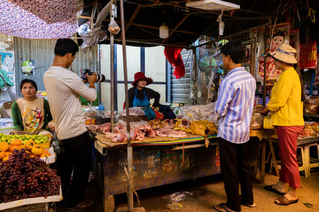Caméra à la main, Sopheak filme Sina et son mari en train d’acheter pour 330 euros de poulets frais au marché de Moung Ruessei (Cambodge), le 15 janvier 2023.