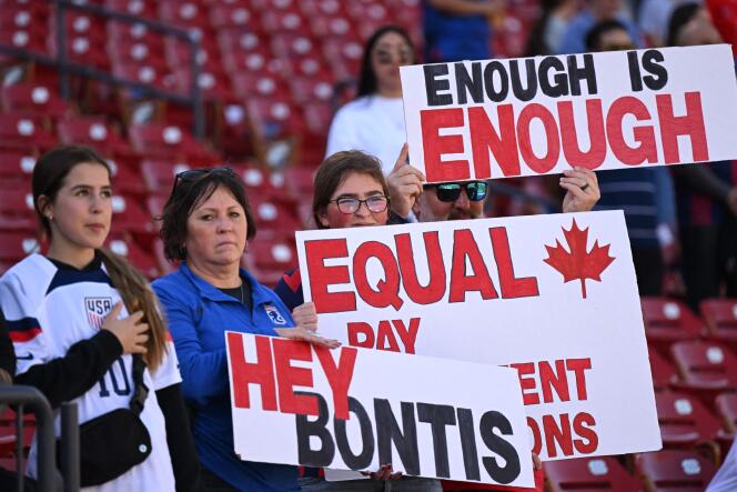 Supporters of Canada's national football team hold signs to denounce inequalities between women and men, during a match against Japan, in Frisco, Texas, on February 22, 2023.