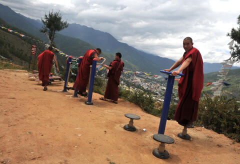 Bhutanese Buddhist monks use exercise machines on a roadside overlooking Thimphu on June 16, 2015. Bhutan -- nestled in the Himalayas and flanked by both India and China -- is renowned for its rich Buddhist culture, and villages are still steeped in its traditions. Protecting the Buddhist culture is a key pillar of Bhutan's unique "Gross National Happiness" development model, which aims to balance spiritual and mental well-being with economic growth. AFP PHOTO/Diptendu DUTTA (Photo by DIPTENDU DUTTA / AFP)