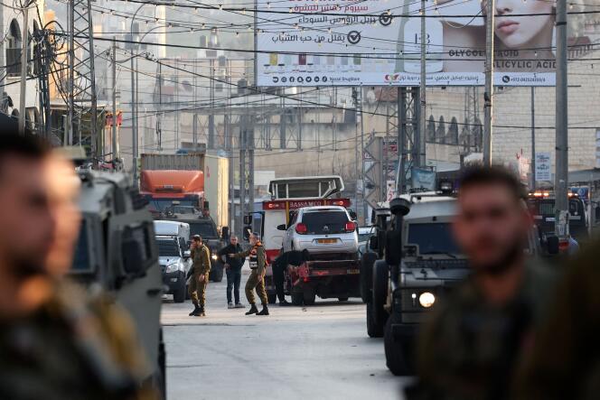 Las fuerzas de seguridad israelíes bloquean una carretera mientras otros remolcan un automóvil al lugar de un ataque en el que murieron dos israelíes en la ciudad ocupada de Hawara, en Cisjordania, el 26 de febrero de 2023. 
