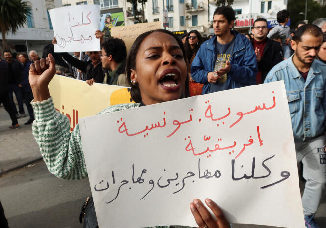 A Tunis, le 25 février 2023, après les propos xénophobes tenus par le président Kaïs Saïed, qui stigmatise les migrants subsahariens sur le territoire tunisien.  Une femme manifeste avec cette banderole : « Féministe, tunisienne et africaine.  Nous sommes tous des femmes et des hommes migrants ».  