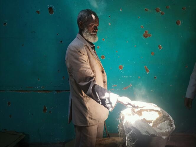 Teklay Tiku, a 71-year-old farmer, in Kerseber, a mountainous village in northern Tigray, on February 23, 2023. He shows a sack of wheat in which Eritrean soldiers have deliberately spoiled the grain with soil.