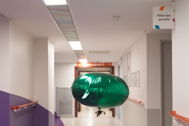 Un drone est attaché à un ballon vert gonflé à l’hélium, et piloté avec un smartphone, dans les couloirs du département d'oncologie pédiatrique de l’Institut Gustave Roussy, à Villejuif (Val-de-Marne), le 14 février 2023.