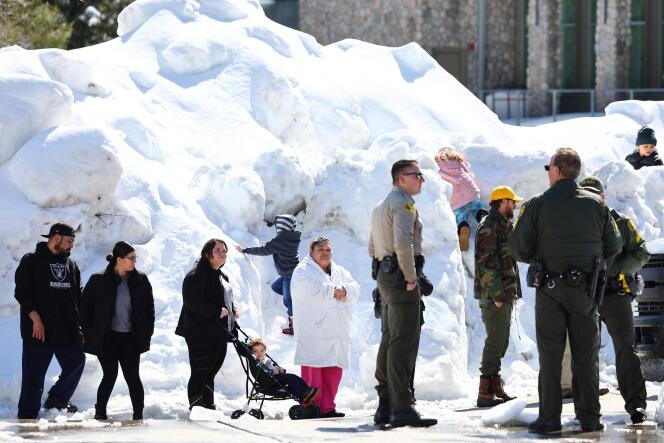 Residents in Crestline, California, wait in line to receive donated food outside the local grocery store, which was severely damaged when its roof collapsed under the weight of several feet of snow, after a series of winter storms in the San Bernardino Mountains in Southern California on March 3, 2023.
