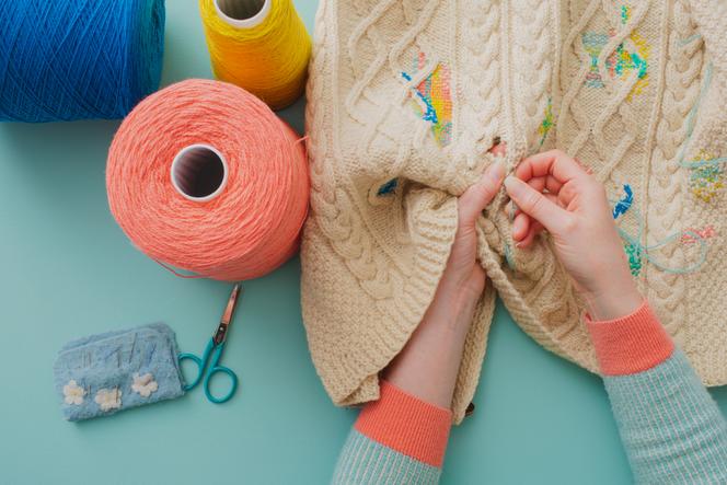 Mending a sweater by Flora Collingwood-Norris.