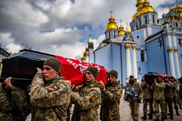 Oekraïense soldaten dragen de doodskisten van Oekraïense vrijwilligers Yuriy Horovets, Maksim Mikhaylov, Taras Karpyuk, Bohdan Lygov na een herdenkingsdienst in het St. Michael's Golden-domed Orthodoxe klooster in Kiev op 7 maart 2023, te midden van de Russische invasie van Oekraïne.  Honderden rouwenden verdringen zich op 7 maart in een kerk in Kiev, voor de begrafenis van vrijwilligers die zijn omgekomen tijdens een sabotagemissie in Rusland, na een reeks aanslagen langs de grenzen van Moskou.  De rouwenden, waarvan velen in camouflagekleding gekleed waren en hun gezicht bedekten, woonden de mis bij in een centrale kerk voor vier mannen - een nog in zijn tienerjaren - die in december werden gedood tijdens een inval in de zuidelijke regio Brjansk in Rusland.  (Foto door Dimitar Delkov/AFP)