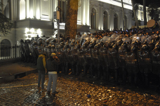 Two protesters stand in front of police line outside the Georgian parliament building in Tbilisi, Georgia, Tuesday, March 7, 2023.