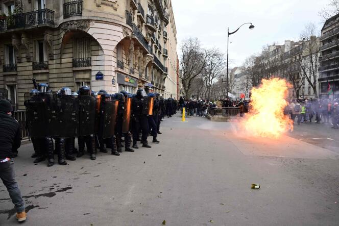 Police stand in formation as a petrol bomb explodes during clashes on the sidelines of a demonstration in Paris.