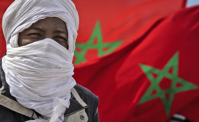 Un homme pose devant des drapeaux marocains à Guerguerat, dans le sud du Sahara occidental, en novembre 2020.