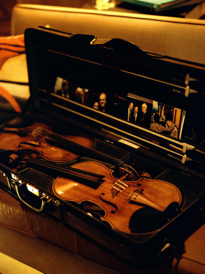 From left to right, the guarneri and the stradivarius on loan from LVMH.  In the lid of the briefcase, two photos of Renaud Capuçon with pianist Nicholas Angelich, another with cellist Yo-Yo Ma and conductor Daniel Barenboim, and one with Eliott, the son he had with Laurence Ferrari, both from behind.  In Paris, on December 12, 2022.