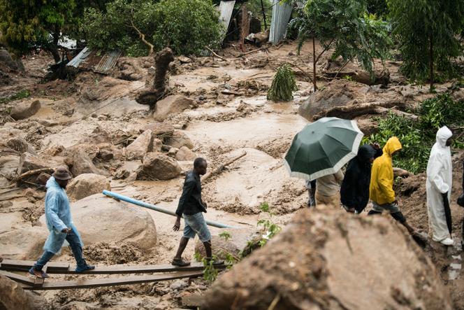 People cross a raging river in Blantyre, Malawi, Monday, March 13, 2023. 