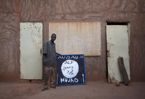 Hotel worker Abderrahmane Toure poses for a picture next to a sign for radical Islamist group Movement for Unity and Jihad in West Africa (MUJAO) in Douentza January 28, 2013. The sign reads, "There is no God but Allah and Mohammad is his prophet." REUTERS/Joe Penney