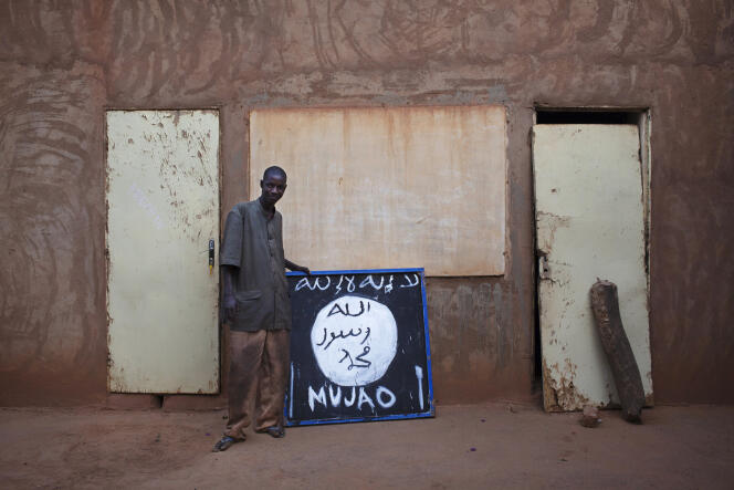 Un Malien pose devant une pancarte du Mouvement pour l’unicité et le djihad en Afrique de l’Ouest (Mujao), à Douentza, en janvier 2013.