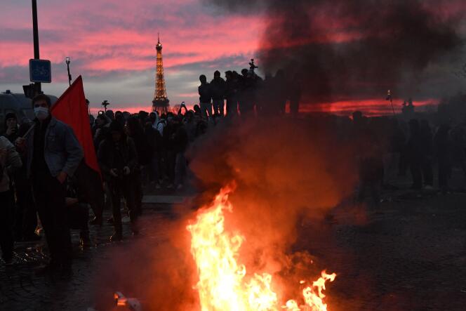 Los manifestantes rodean las barreras en llamas durante una manifestación en la Plaza de la Concordia, con la Torre Eiffel al fondo, en París, el 16 de marzo de 2023.