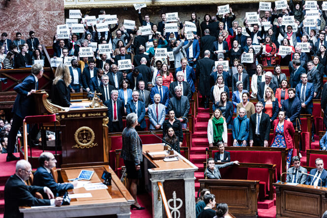 As French Prime Minister Elisabeth Borne takes her place at the Assemblee Nationale podium, left-wing MPs hold up signs reading 