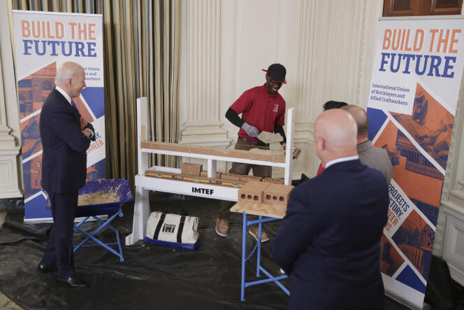 US President Joe Biden observes Jamaar Evans, an apprentice mason, trained by unions and big business, in the State Dining Room of the White House on November 2, 2022, in Washington, DC.