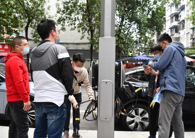 Un homme utilise son smartphone pour scanner le code QR afin de recharger un véhicule électrique à une borne de recharge, à Chengdu, dans la province chinoise du Sichuan (Chine), le 14 octobre 2022.