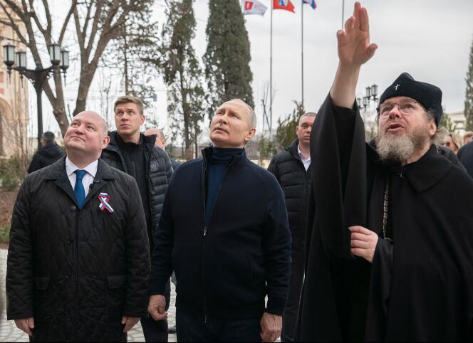 This handout photograph taken and released by the Russian presidential press office in Sevastopol on March 18, 2023, shows Russian President Vladimir Putin (L), flanked by Sevastopol Governor Mikhail Razvozhayev (C), listening to Metropolitan Tikhon Shevkunov (R), chairman of the Patriarchal Council for Culture, as he visits the Chersonesos Taurica historical and archeological park on the 9th anniversary of the referendum on the state status of Crimea and Sevastopol and its reunification with Russia. 
