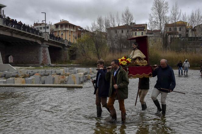 Des pénitents portent la statue de saint Gaudéric, patron des agriculteurs, dans le fleuve Têt, à Perpignan, le 18 mars 2023.