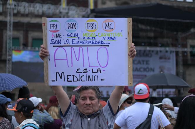 Un partisan du président Andres Manuel Lopez Obrador avec une pancarte citant les partis d’opposition qui « sont la maladie, AMLO est le médicament », lors de la manifestation en faveur du président mexicain, sur la place du Zocalo, à Mexico, le 18 mars 2023.  