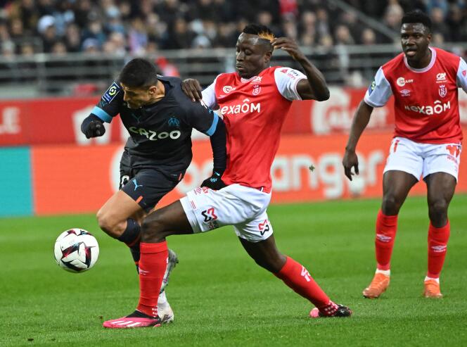 L’attaquant chilien de Marseille, Alexis Sanchez (maillot noir) tente d’échapper au Rémois Folarin Balogun, lors de la 28ᵉ journée de Ligue 1, le 19 mars 2023, au stade Auguste-Delaune de Reims.