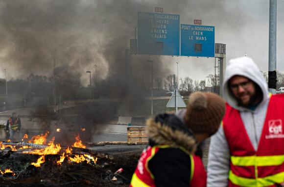 Des syndicalistes prennent part à une action de blocage, devant un feu allumé, dans la zone industrielle du Havre, le 21 mars 2023 au matin.
