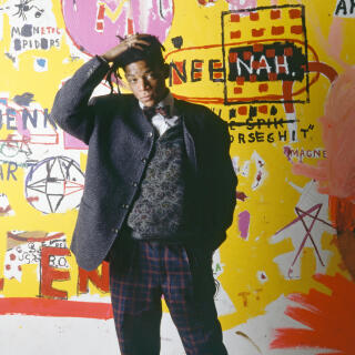 American artist, musician and producer of Haitian and Puerto Rican origins Jean-Michel Basquiat, in front of one of his paintings, during an exhibition at the Yvon Lambert gallery in Paris (Photo by)