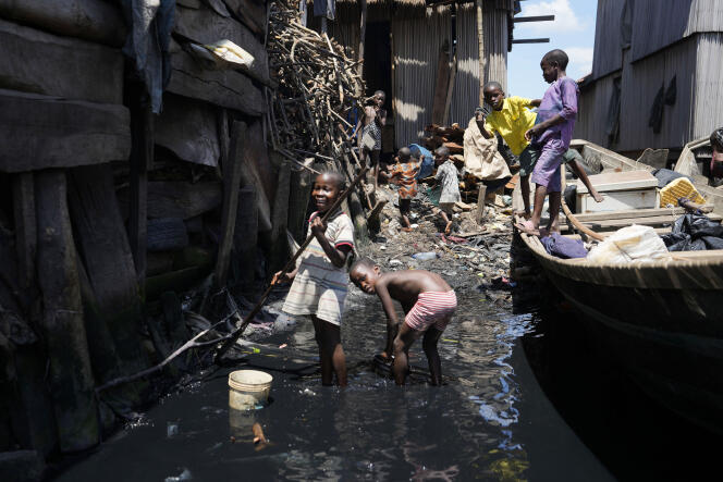 Des enfants jouent dans une eau sale entourée d’ordures, dans le bidonville flottant de Makoko, à Lagos, la capitale économique du Nigeria, le 20 mars 2023.