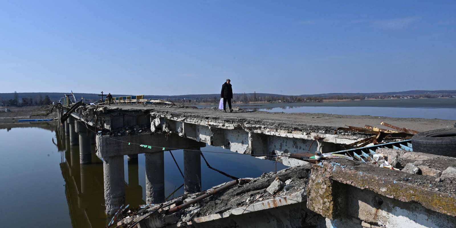 Un habitant traverse la rivière Siverskyi Donets sur une passerelle aménagée sur un ancien pont routier détruit par des bombardements, à Staryi Saltiv, dans l’est de Kharkiv, le 22 mars 2023.