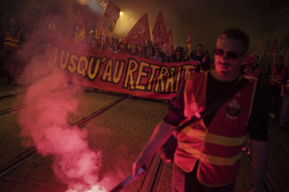 Des cheminots tiennent une banderole portant l’inscription « Jusqu’au retrait » lors d’une manifestation contre la réforme des retraites à Lyon, le 22 mars 2023.