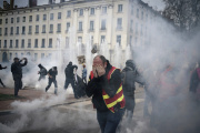 Protesters run amid the tear gas during a demonstration in Lyon, central France, Thursday, March 23, 2023.