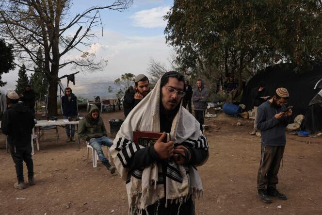 Israeli settlers pray in the former settlement of Homesh, west of the West Bank city of Nablus, December 30, 2021.