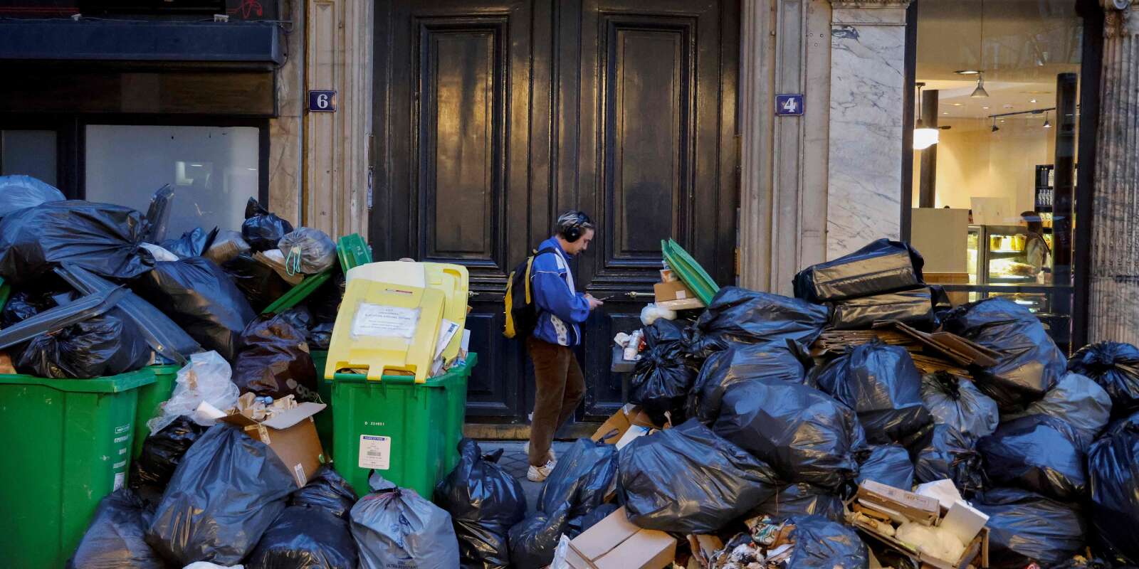 Un homme passe devant une pile de sacs poubelles qui se sont accumulés depuis que les éboueurs se sont mis en grève contre la réforme des retraites proposée par le gouvernement français, à Paris le 20 mars 2023. 